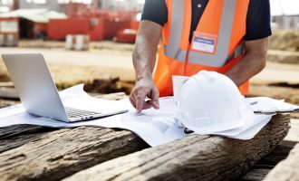Closeup of contractor in construction site pointing at plan on wooden sleeper